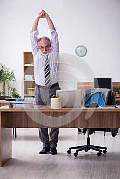 Old male employee suffering from radiculitis at workplace