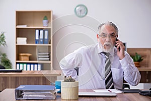 Old male employee suffering from radiculitis at workplace