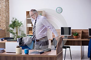 Old male employee suffering from radiculitis at workplace