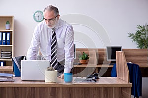 Old male employee suffering from radiculitis at workplace