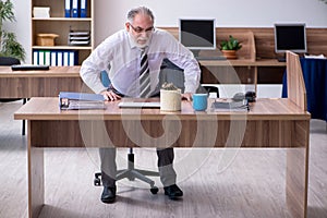 Old male employee suffering from radiculitis at workplace