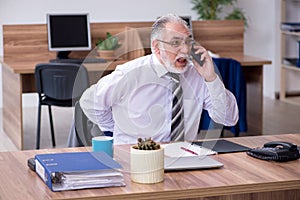 Old male employee suffering from radiculitis at workplace