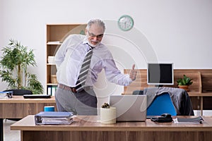 Old male employee suffering from radiculitis at workplace