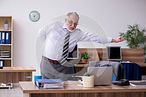 Old male employee suffering from radiculitis at workplace