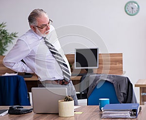 Old male employee suffering from radiculitis at workplace