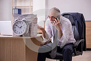 Old male employee in time manegement concept photo