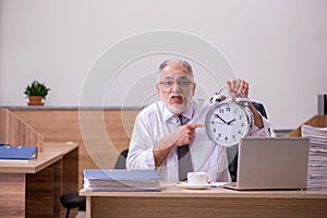 Old male employee in time manegement concept