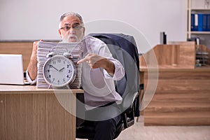 Old male employee in time manegement concept photo