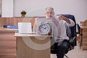 Old male employee in time manegement concept photo