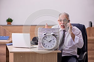 Old male employee in time manegement concept photo