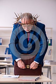 Old male employee wearing prickly wreath on head