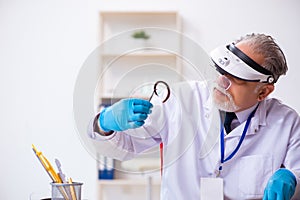 Old male expert criminologist working in the lab for evidence