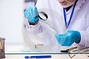 Old male expert criminologist working in the lab for evidence