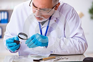 Old male expert criminologist working in the lab for evidence