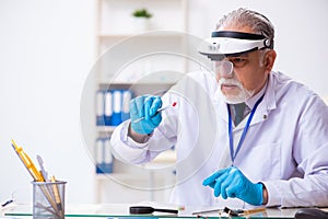 Old male expert criminologist working in the lab for evidence