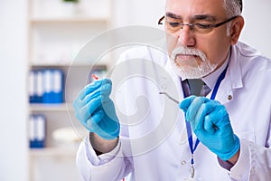 Old male expert criminologist working in the lab for evidence
