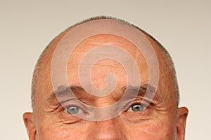 Old male eyes and wrinkled forehead, part of the face close-up, overhang, the concept of age-related changes in human skin