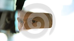 Old male face reflecting in rear-view mirror, taxi driver, traffic safety, car