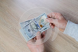 Old male hands hold paper dollars banknotes in his hands, counting a bundle of money, concept of cash, payments, savings