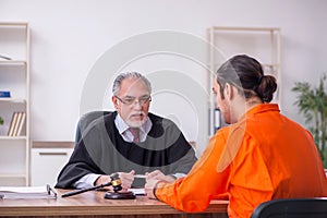 Old male judge meeting with young captive in courthouse