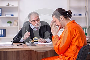 Old male judge meeting with young captive in courthouse