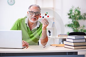 Old male student physicist studying molecular model