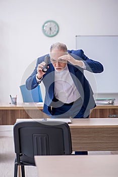 Old male teacher holding penlight in the classroom