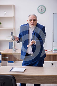 Old male teacher holding penlight in the classroom