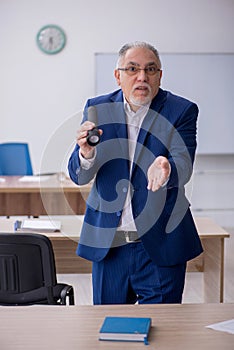 Old male teacher holding penlight in the classroom