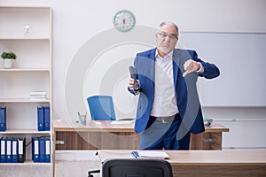 Old male teacher holding penlight in the classroom