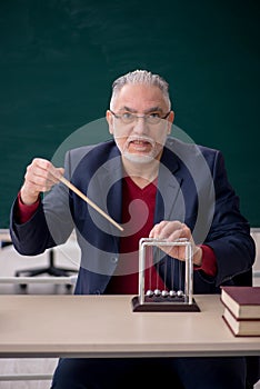 Old male teacher physicist sitting in the classroom