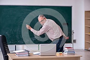 Old male teacher sitting in the classroom