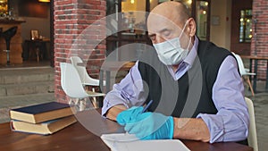 Old male teacher works with protective mask and gloves in university canteen or college cafeteria