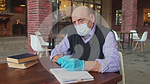 Old male teacher works with protective mask and gloves in university canteen or college cafeteria