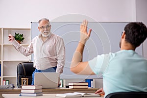 Old male teacher and young male student in the classroom