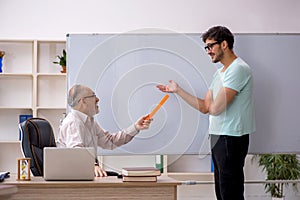 Old male teacher and young male student in the classroom