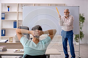 Old male teacher and young male student in the classroom