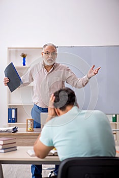 Old male teacher and young male student in the classroom