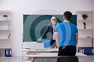 Old male teacher and young male student in front of blackboard