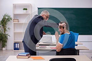 Old male teacher and young male student in front of blackboard