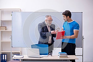 Old male teacher and young male student in front of whiteboard
