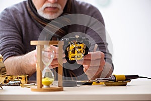 Old male watchmaker working in the workshop