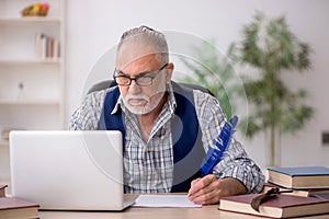 Old male writer sitting at workplace