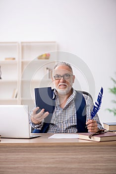 Old male writer sitting at workplace