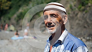 Old man on the beach. Cheerful man smiling and squinting enjoying vacation