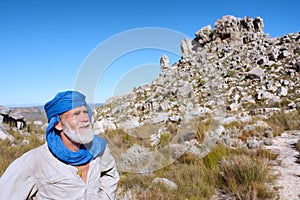 Old man in bedouin clothes looks at mountains