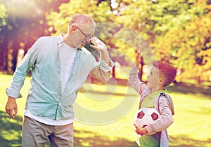 Old man and boy with soccer ball making high five