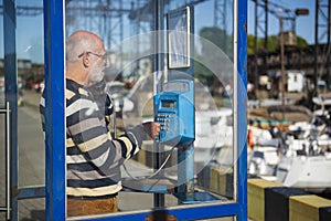 An old man is calling from a payphone