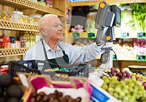 Old man cashier standing at counter in greengrocer