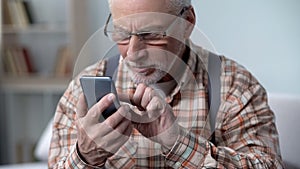 Old man cautiously using smartphone, learning apps and new technologies, closeup